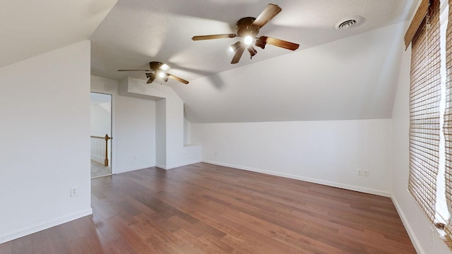 bonus room featuring dark hardwood / wood-style floors, ceiling fan, a textured ceiling, and vaulted ceiling