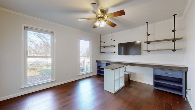 kitchen with crown molding, dark wood-type flooring, ceiling fan, and built in desk