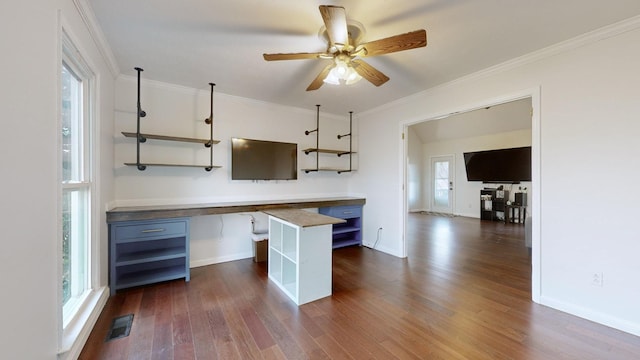 kitchen featuring ceiling fan, plenty of natural light, built in desk, and dark hardwood / wood-style floors