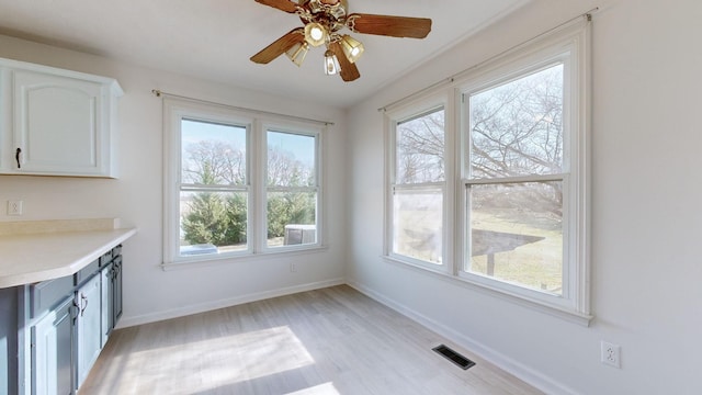 unfurnished dining area with ceiling fan and light wood-type flooring