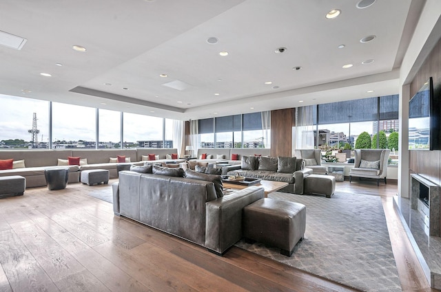 living room featuring a raised ceiling, a fireplace, plenty of natural light, and hardwood / wood-style flooring