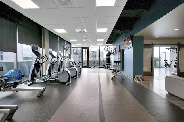 exercise room with a drop ceiling and a healthy amount of sunlight