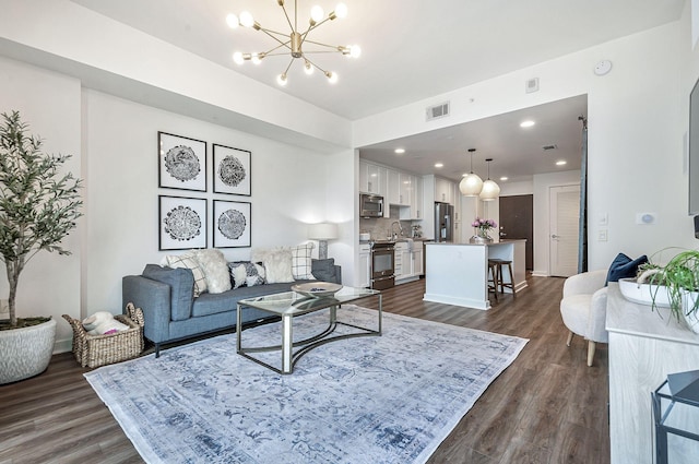 living room with dark hardwood / wood-style floors, a notable chandelier, and sink