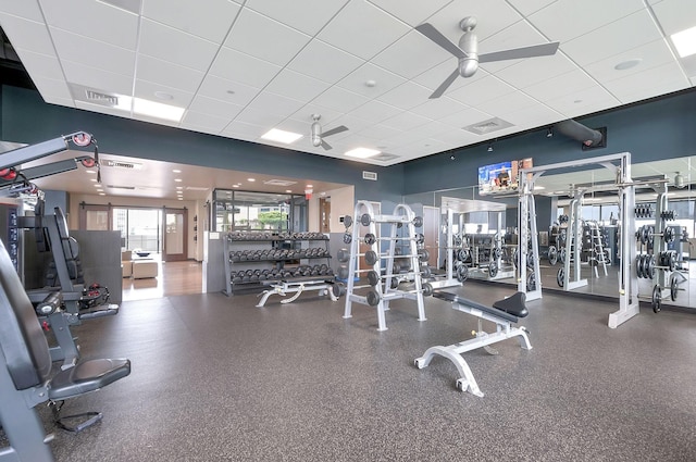 gym with a paneled ceiling and ceiling fan