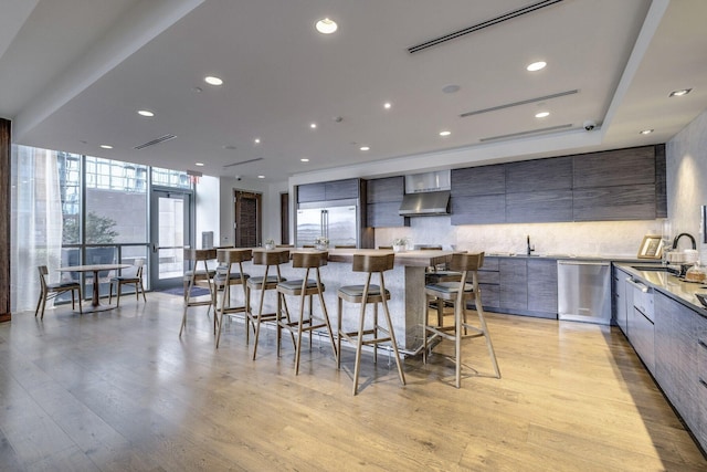 kitchen with sink, stainless steel appliances, a wall of windows, a breakfast bar, and light wood-type flooring