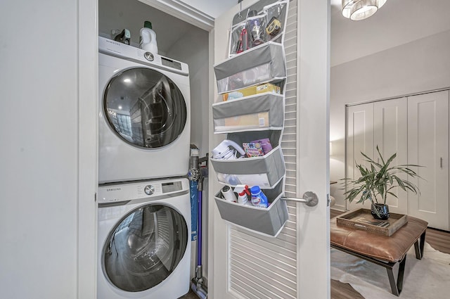 clothes washing area with hardwood / wood-style floors and stacked washer / dryer