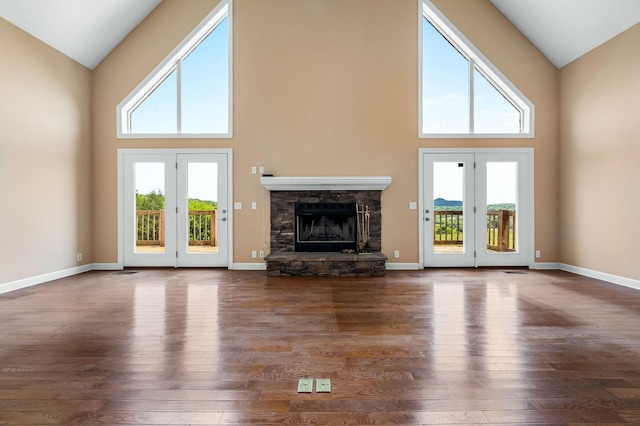 unfurnished living room featuring a fireplace, a towering ceiling, and dark wood-type flooring