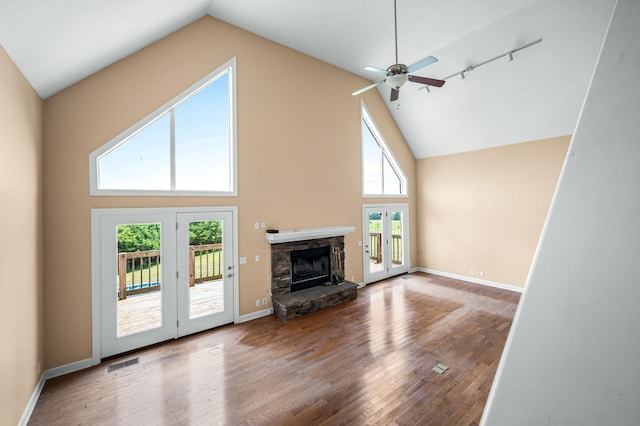 unfurnished living room with hardwood / wood-style floors, ceiling fan, a fireplace, and french doors