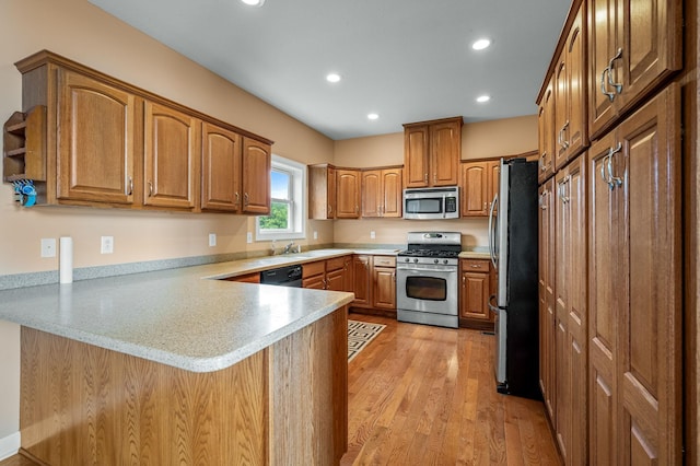 kitchen featuring kitchen peninsula, stainless steel appliances, light hardwood / wood-style floors, and sink