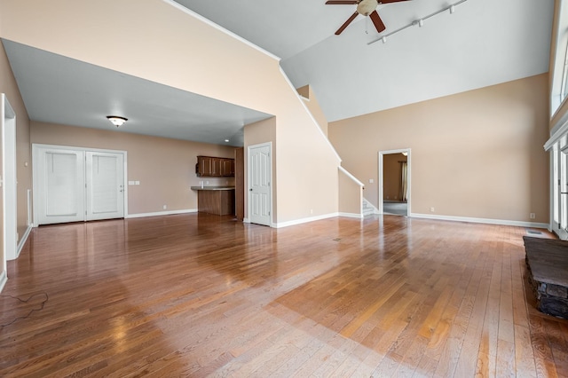 unfurnished living room featuring ceiling fan, wood-type flooring, and high vaulted ceiling