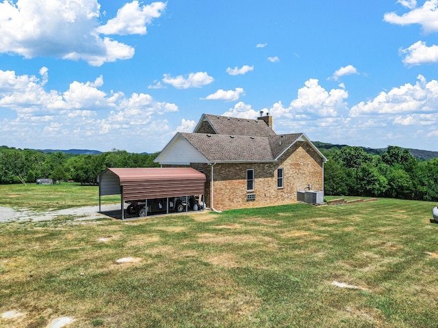 back of property featuring a lawn, central AC, and a carport