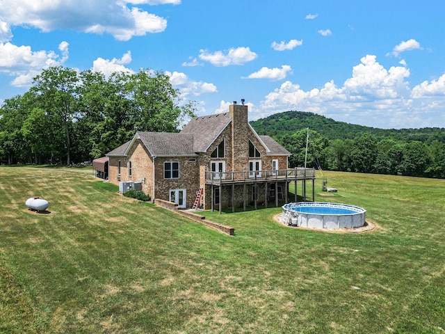 back of property featuring a deck and a lawn