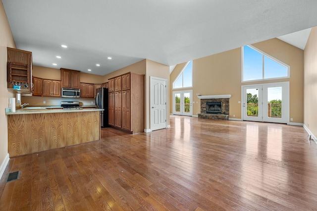 kitchen with kitchen peninsula, stainless steel appliances, a wealth of natural light, and light hardwood / wood-style floors