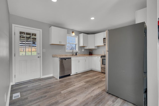 kitchen featuring sink, white cabinetry, stainless steel appliances, and light hardwood / wood-style flooring