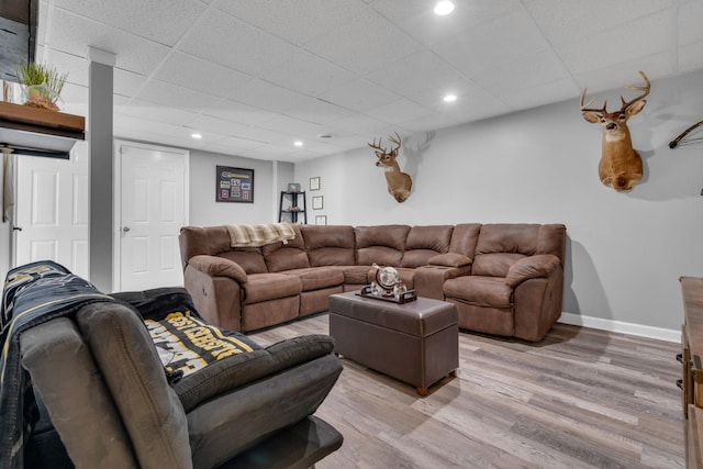 living room with a drop ceiling and light wood-type flooring