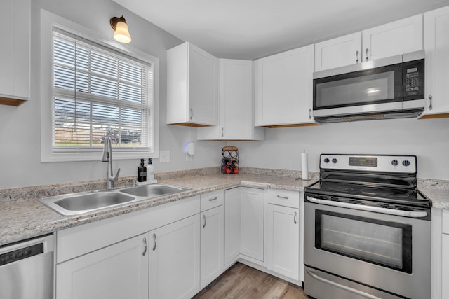 kitchen with sink, white cabinets, stainless steel appliances, and light hardwood / wood-style floors