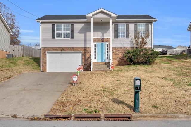 raised ranch featuring a garage, central air condition unit, and a front lawn