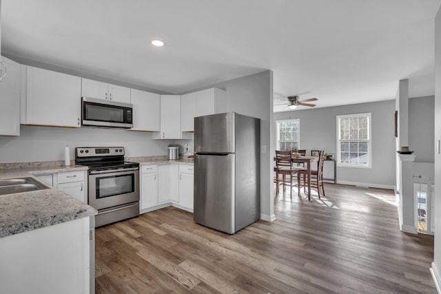 kitchen featuring appliances with stainless steel finishes, ceiling fan, sink, white cabinets, and hardwood / wood-style floors