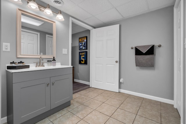 bathroom with tile patterned floors, a drop ceiling, and vanity