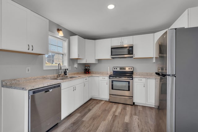 kitchen with sink, white cabinetry, stainless steel appliances, and light wood-type flooring