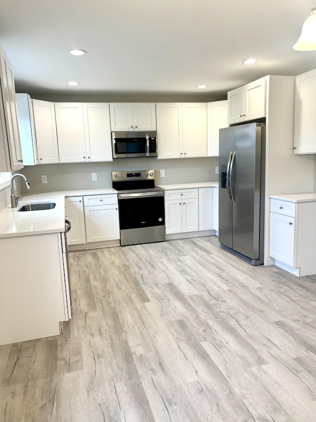 kitchen featuring white cabinets, light wood-type flooring, sink, and appliances with stainless steel finishes