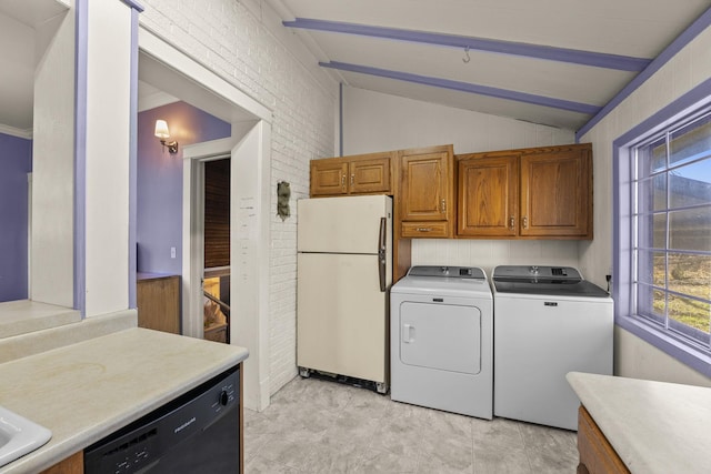 clothes washing area featuring washing machine and dryer and brick wall