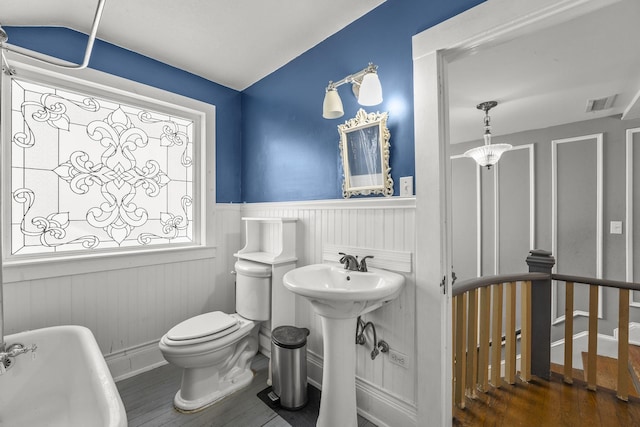 bathroom with sink, vaulted ceiling, hardwood / wood-style flooring, toilet, and a tub to relax in