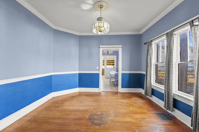 unfurnished room with wood-type flooring, an inviting chandelier, and ornamental molding