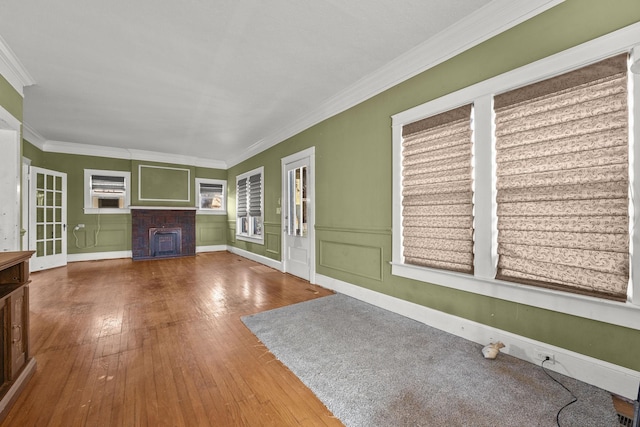 unfurnished living room featuring hardwood / wood-style flooring, crown molding, and a fireplace