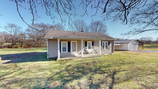 rear view of property featuring a lawn, covered porch, and an outdoor structure