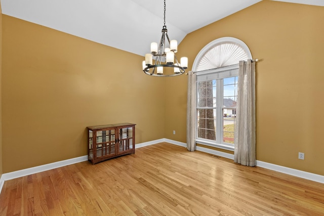 spare room featuring a chandelier, light hardwood / wood-style floors, and vaulted ceiling