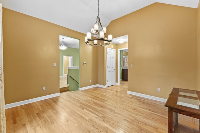 unfurnished dining area featuring an inviting chandelier, light hardwood / wood-style floors, and vaulted ceiling