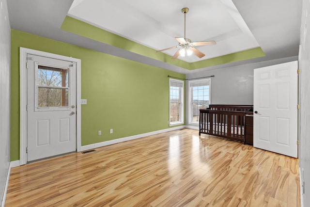 unfurnished bedroom with a raised ceiling and light hardwood / wood-style floors