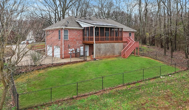 rear view of property featuring a yard, a garage, a wooden deck, and a sunroom