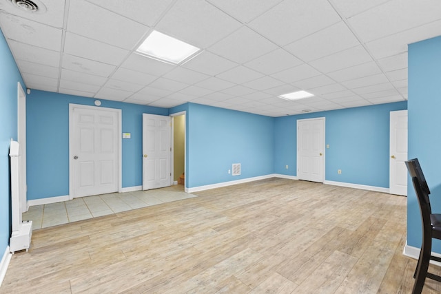 basement with a drop ceiling and light hardwood / wood-style floors