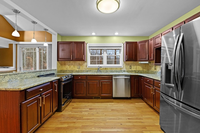 kitchen featuring tasteful backsplash, light stone counters, hanging light fixtures, and appliances with stainless steel finishes