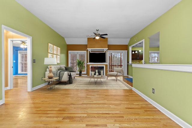 living room with light hardwood / wood-style floors, lofted ceiling, and a fireplace