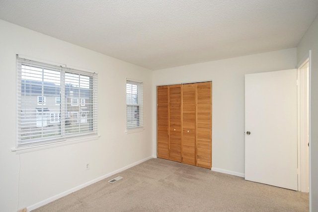 unfurnished bedroom featuring light carpet and a closet