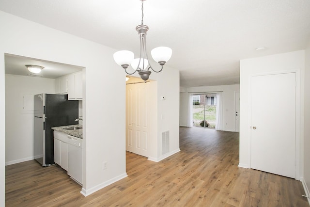 kitchen featuring light wood-type flooring, white cabinetry, hanging light fixtures, and an inviting chandelier