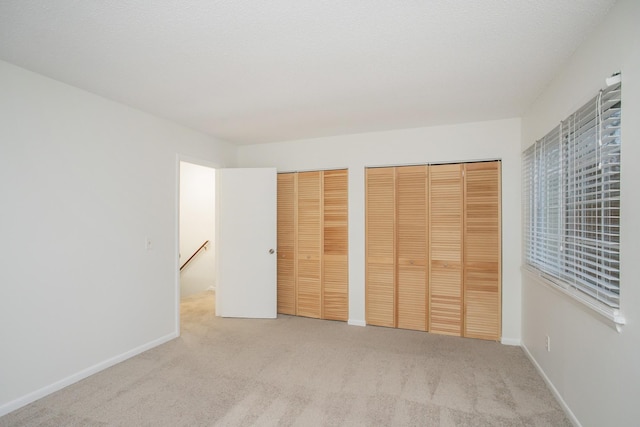 unfurnished bedroom featuring two closets and light colored carpet