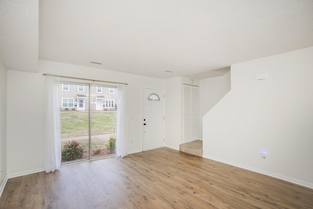 interior space featuring light wood-type flooring and a textured ceiling