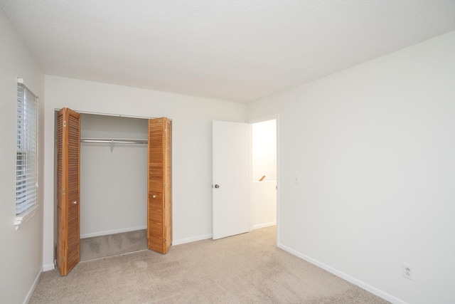 unfurnished bedroom with light colored carpet, a textured ceiling, and a closet