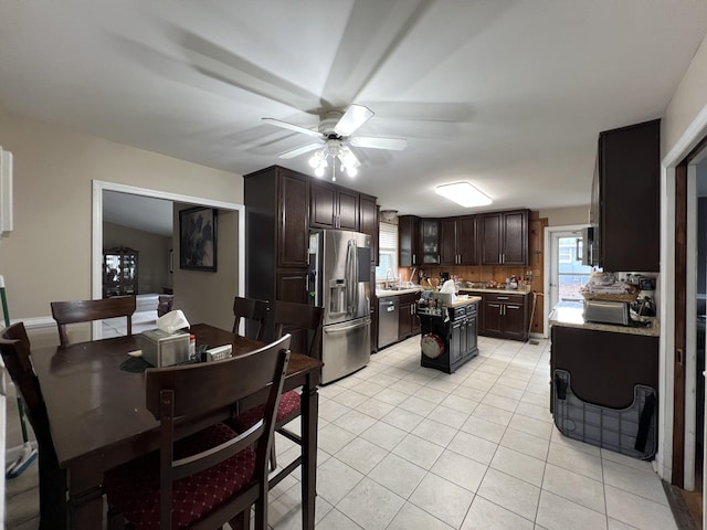 kitchen with a center island, backsplash, stainless steel refrigerator with ice dispenser, light tile patterned floors, and dark brown cabinets