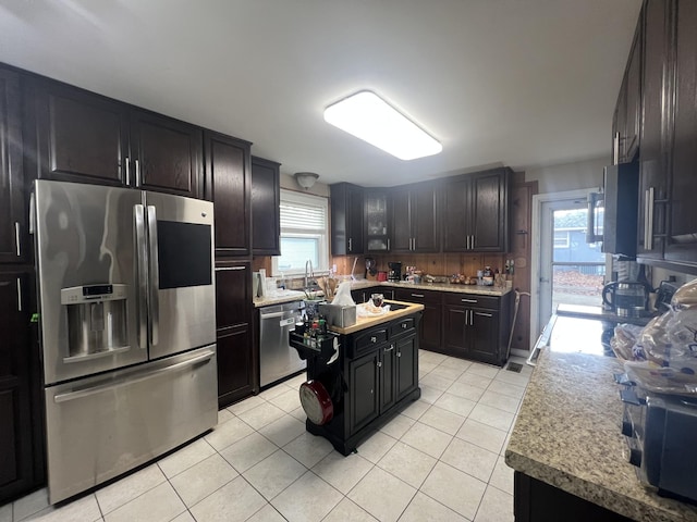 kitchen featuring a center island, a healthy amount of sunlight, light tile patterned flooring, and stainless steel appliances