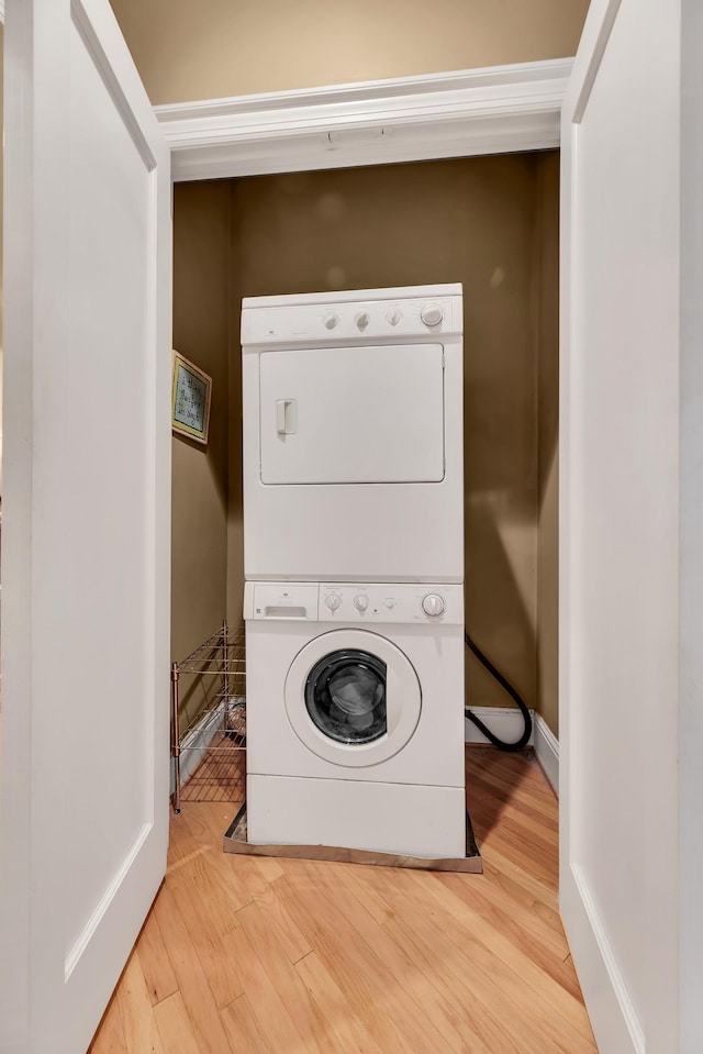 laundry area featuring light hardwood / wood-style floors and stacked washer / drying machine