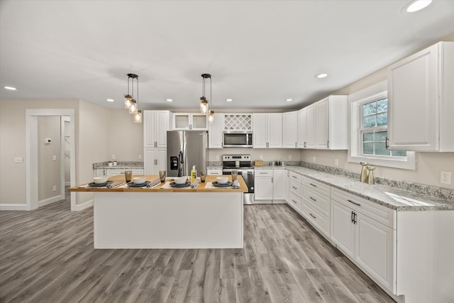 kitchen featuring a center island, hanging light fixtures, light hardwood / wood-style floors, white cabinetry, and stainless steel appliances