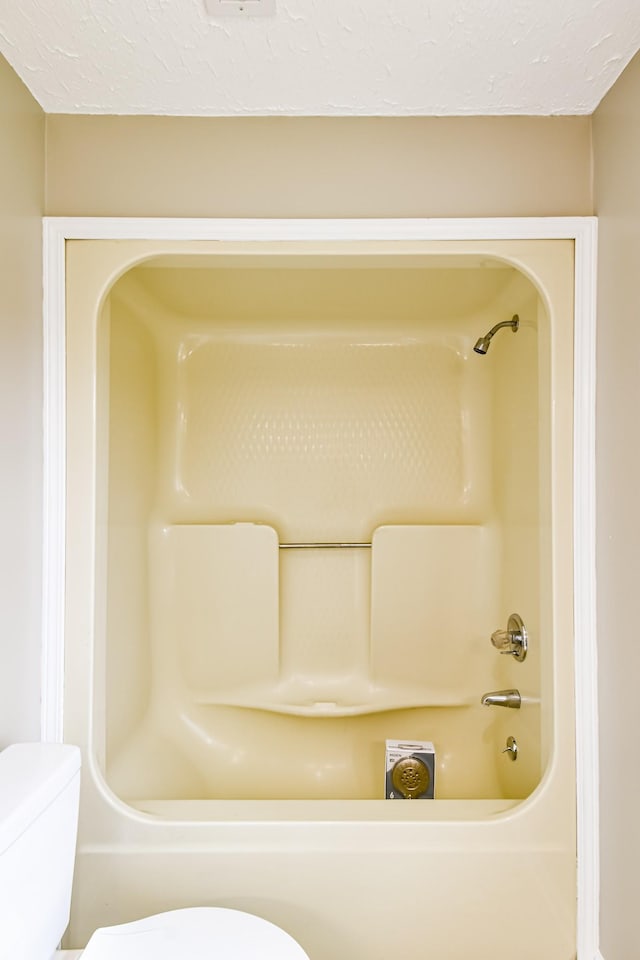 bathroom featuring shower / tub combination, a textured ceiling, and toilet