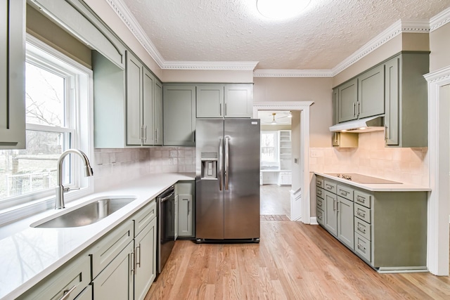 kitchen with decorative backsplash, appliances with stainless steel finishes, a textured ceiling, sink, and light hardwood / wood-style flooring