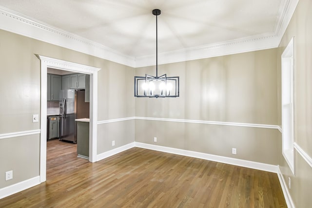 unfurnished dining area featuring hardwood / wood-style flooring, a notable chandelier, and crown molding