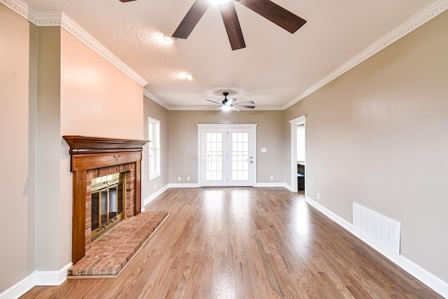 unfurnished living room featuring a textured ceiling, ceiling fan, crown molding, a fireplace, and hardwood / wood-style floors